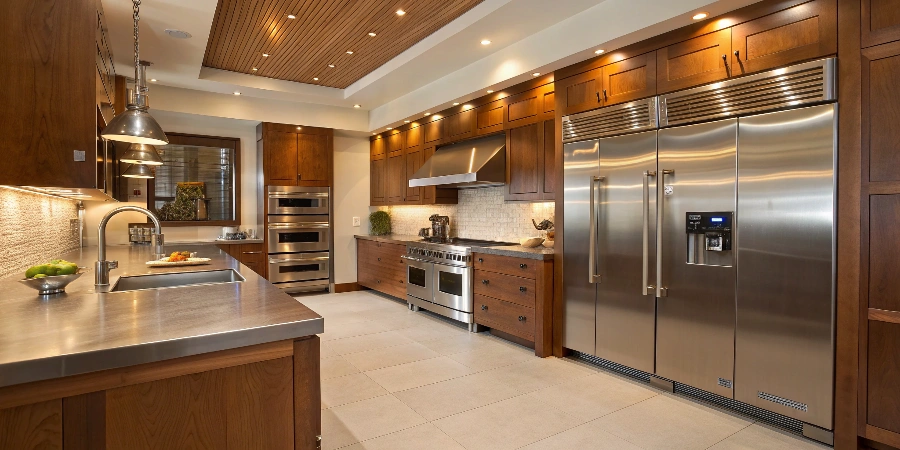A hybrid kitchen design mixing stainless steel base cabinets with warm wood upper cabinets and a quartz island